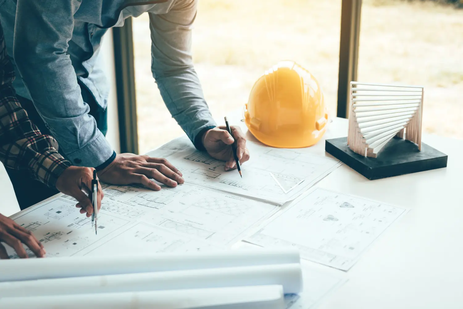 Zwei Ingenieure oder Mitarbeiter, die an einem Projekt arbeiten und gemeinsam diskutieren, während sie sich die Baupläne ansehen.ngineering man or co-workers working on a project and discussing together with looking at blueprint paperwork. 